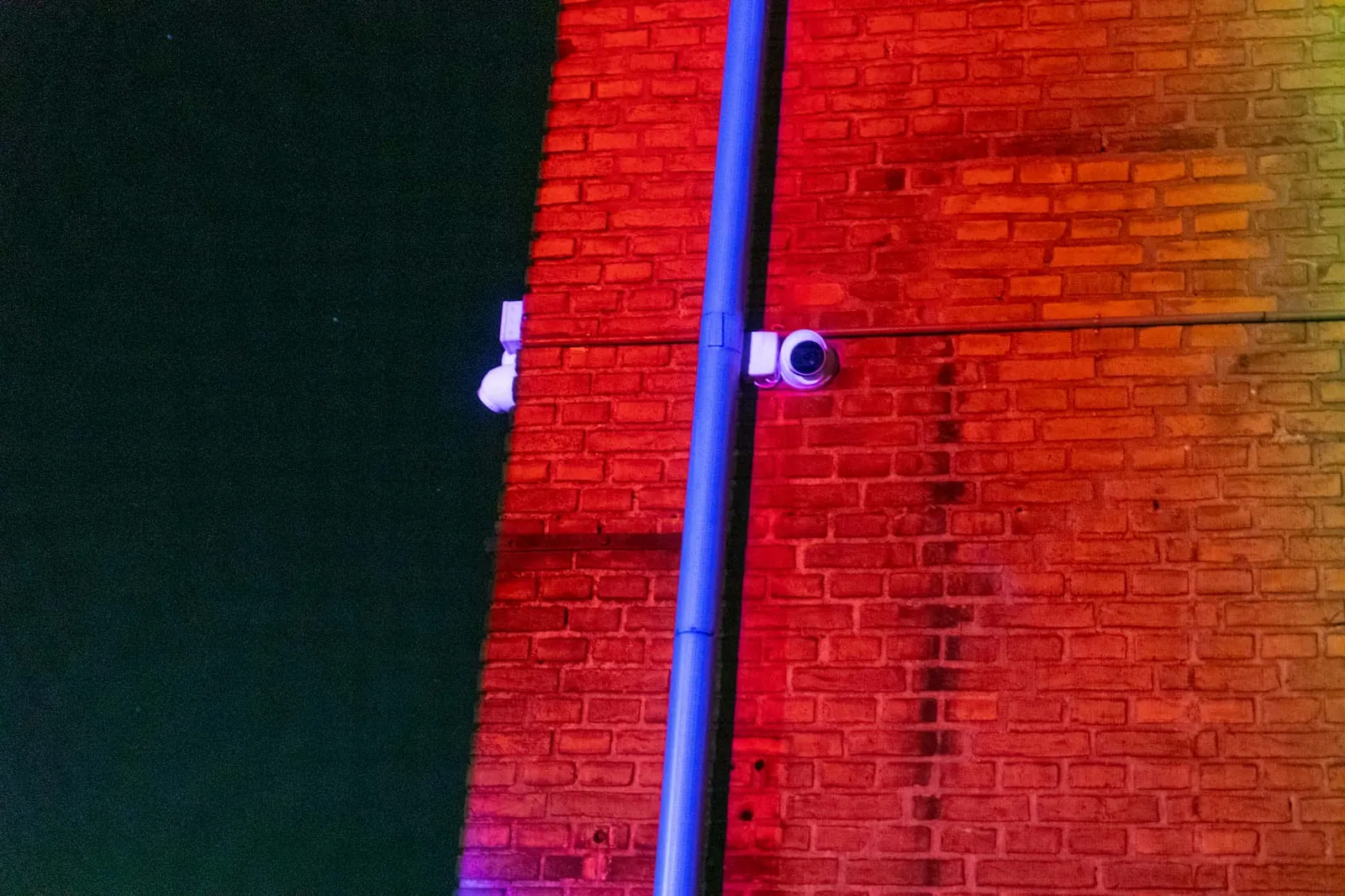 Red and blue video mapping projected onto an old brick building at night.