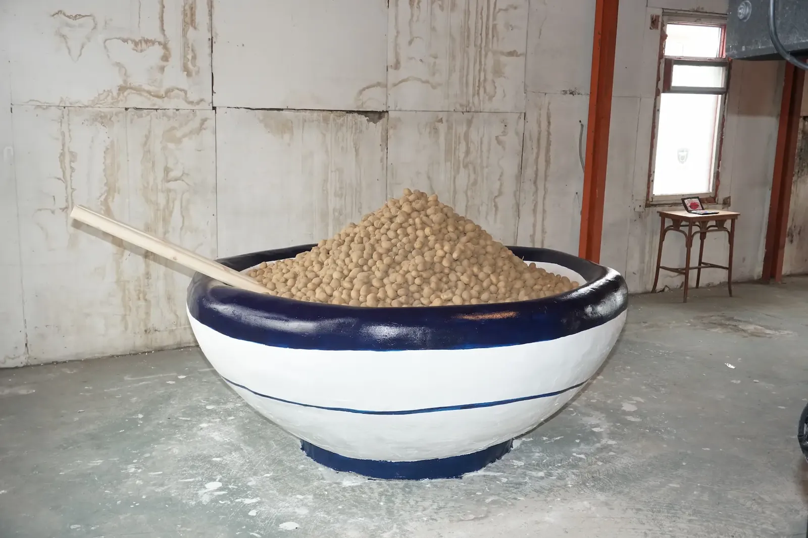The oversized bowl seen from the side, filled with potatoes.